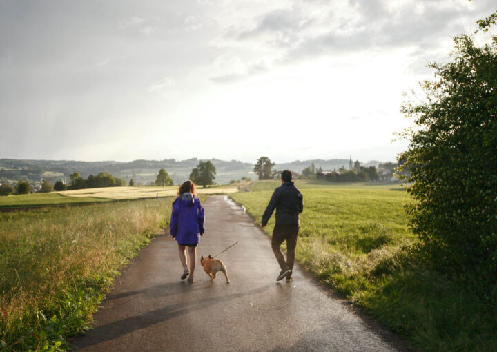 A coulpe walking a country road with a dog